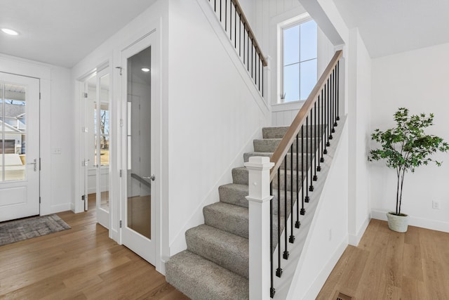 stairs featuring a wealth of natural light, baseboards, and wood finished floors