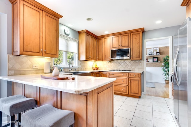 kitchen with light tile patterned floors, stainless steel appliances, a peninsula, and light countertops