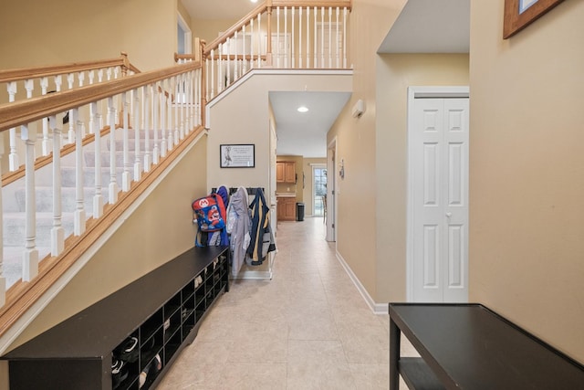 hallway featuring tile patterned floors, baseboards, and stairs