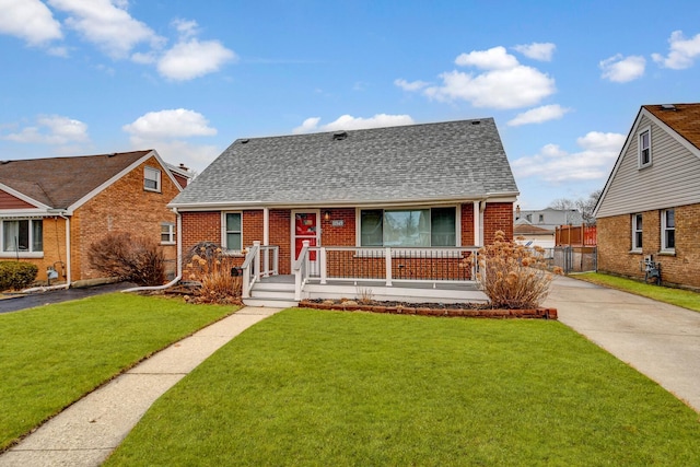 view of front of property with driveway, covered porch, a front yard, and brick siding