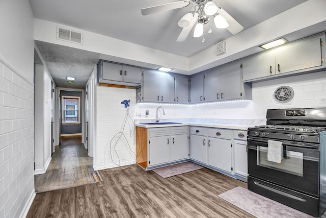 kitchen with visible vents, dark wood-style flooring, gray cabinetry, a sink, and gas stove