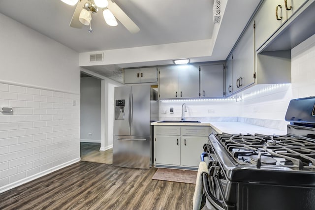 kitchen featuring black gas range, a sink, visible vents, stainless steel fridge, and dark wood finished floors