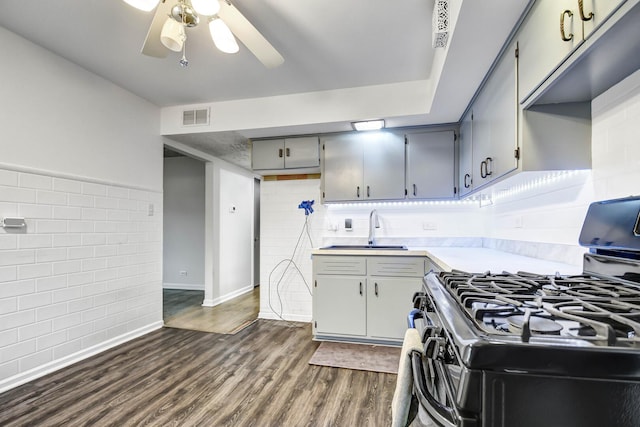 kitchen featuring dark wood-type flooring, a sink, visible vents, light countertops, and range with gas cooktop