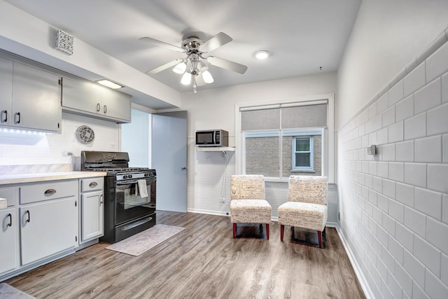 kitchen featuring light countertops, visible vents, black range with gas stovetop, ceiling fan, and light wood-type flooring