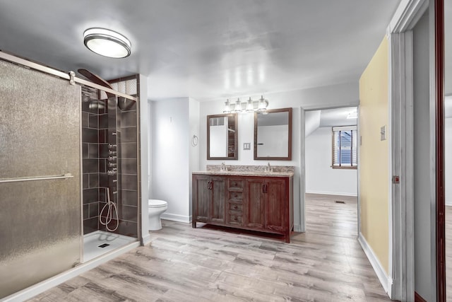 full bathroom featuring a sink, a shower stall, toilet, and wood finished floors