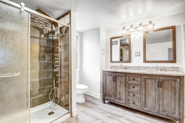 full bath featuring toilet, a stall shower, a sink, and wood finished floors