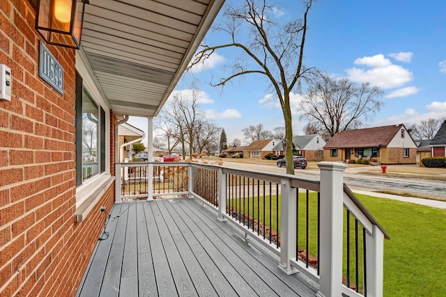 deck with covered porch, a lawn, and a residential view