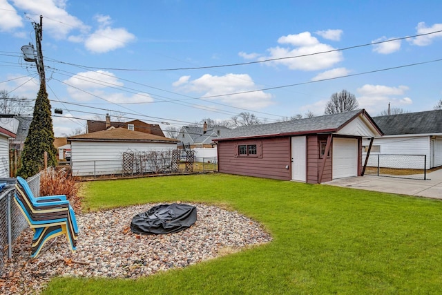 view of yard with a garage, an outbuilding, fence, and a fire pit