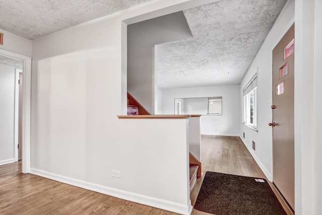 interior space featuring baseboards, a textured ceiling, stairway, and wood finished floors