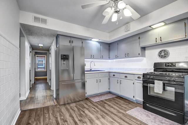 kitchen with a sink, stainless steel refrigerator with ice dispenser, black gas range, and dark wood-style floors