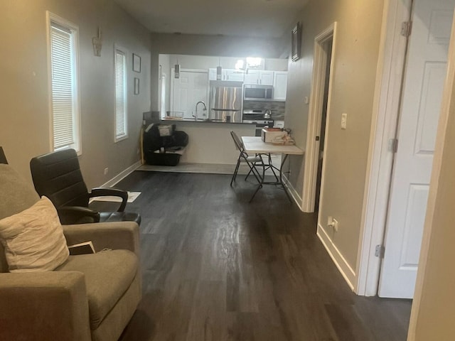 interior space featuring appliances with stainless steel finishes, white cabinets, dark wood-type flooring, and a peninsula