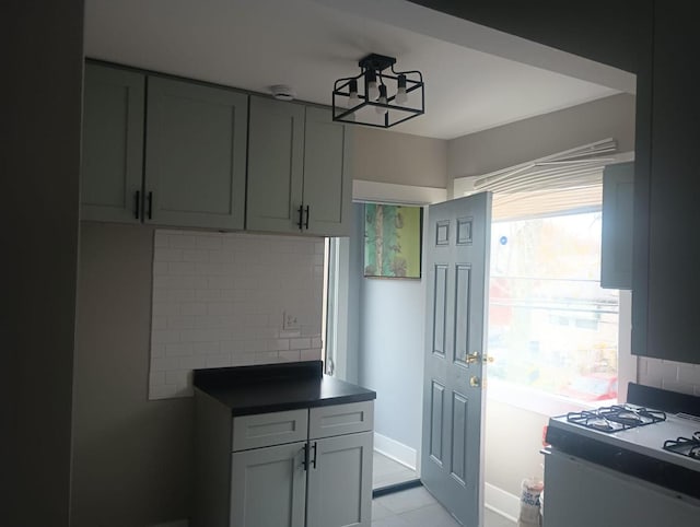 kitchen with dark countertops, baseboards, backsplash, and range with gas cooktop