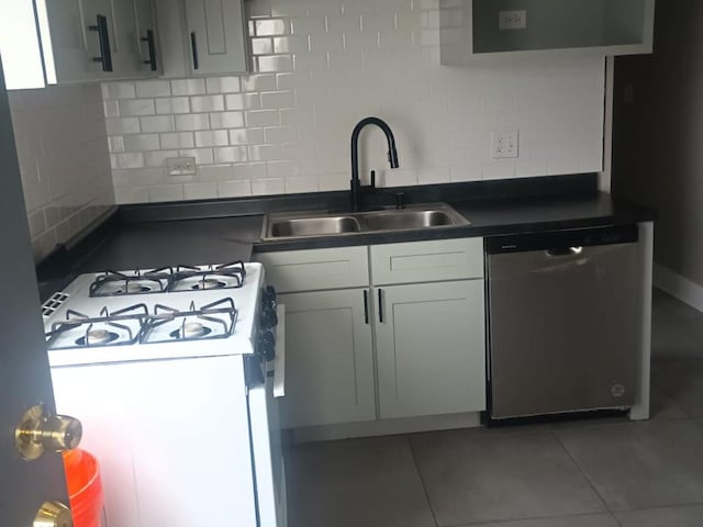 kitchen featuring tasteful backsplash, dark countertops, white gas range, stainless steel dishwasher, and a sink