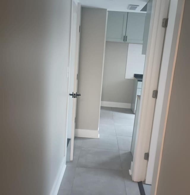 corridor with light tile patterned floors, baseboards, and visible vents