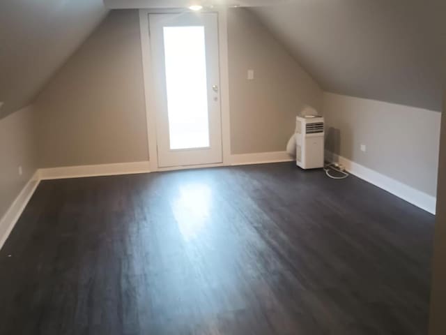 additional living space featuring lofted ceiling, dark wood finished floors, and baseboards