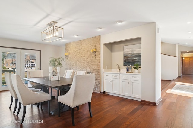 dining space with dark wood finished floors, wet bar, and recessed lighting