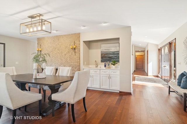 dining area featuring baseboards, dark wood-type flooring, an accent wall, and vaulted ceiling