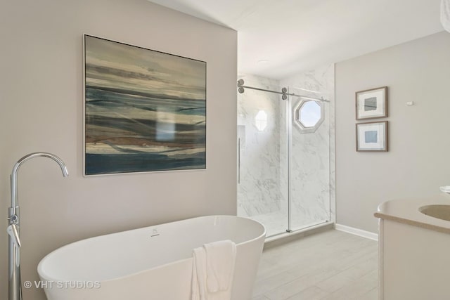 bathroom featuring a marble finish shower, a soaking tub, vanity, and baseboards