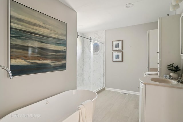 full bathroom featuring a marble finish shower, baseboards, a freestanding tub, wood finished floors, and vanity