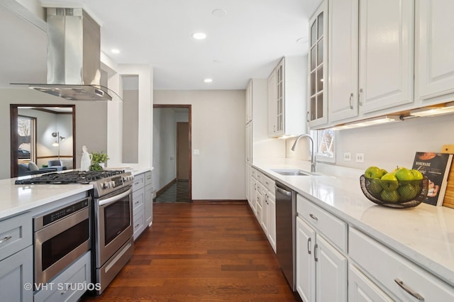 kitchen featuring dark wood finished floors, island exhaust hood, a sink, white cabinets, and appliances with stainless steel finishes