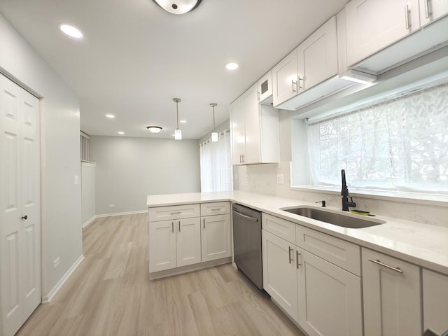 kitchen featuring a sink, white cabinetry, light countertops, stainless steel dishwasher, and light wood finished floors