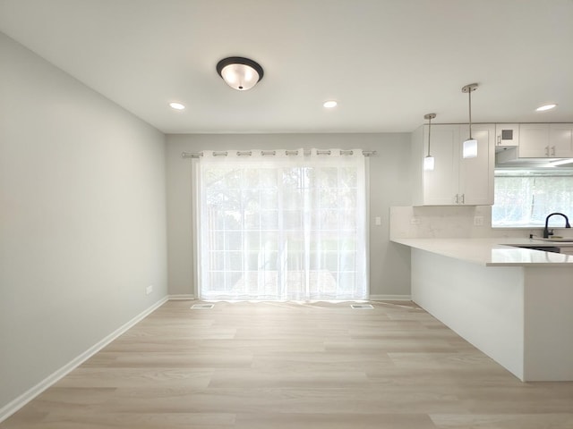 kitchen with a healthy amount of sunlight, light countertops, decorative backsplash, and white cabinetry