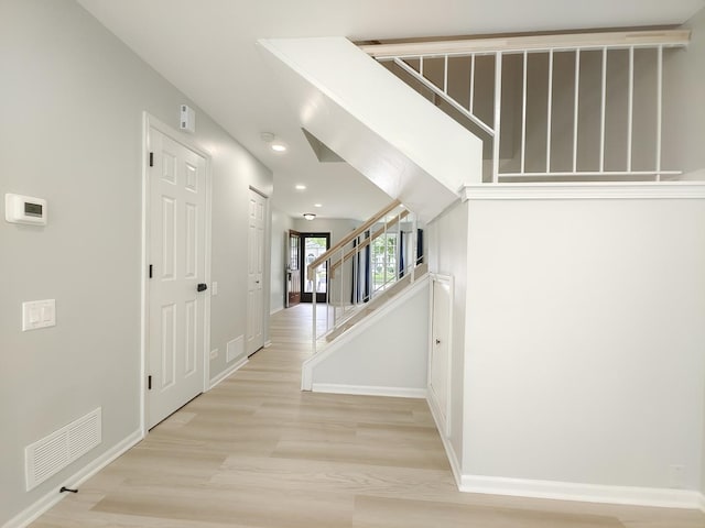 hall featuring baseboards, stairway, visible vents, and light wood-style floors