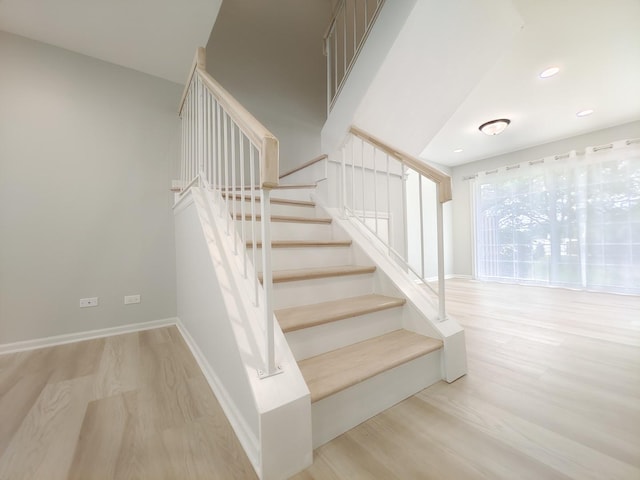 stairway featuring baseboards, wood finished floors, and recessed lighting