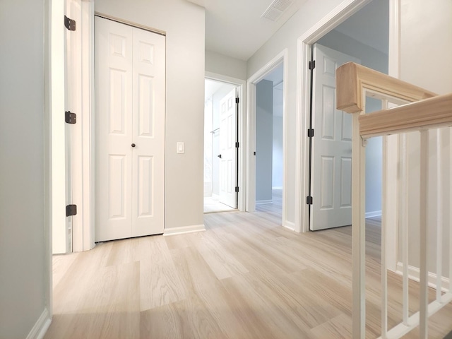 corridor featuring visible vents, light wood-style flooring, and baseboards