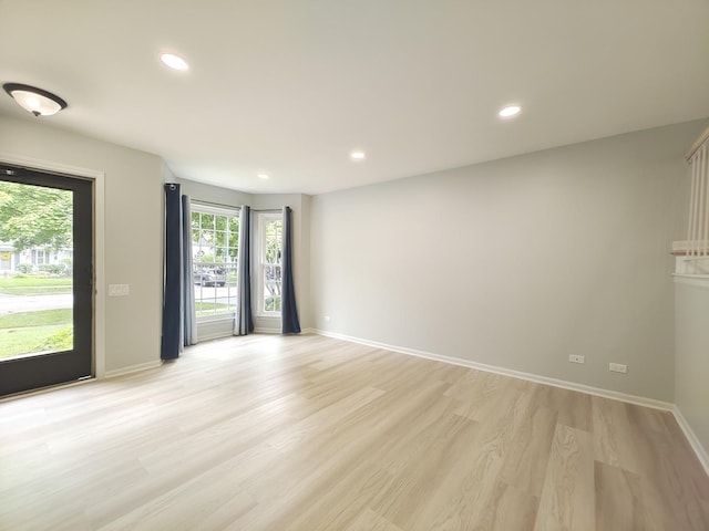 spare room with baseboards, light wood finished floors, and recessed lighting