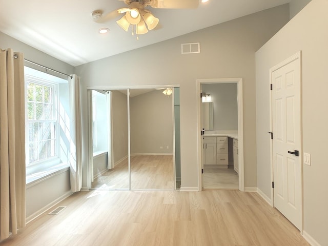 unfurnished bedroom featuring light wood-style floors, baseboards, visible vents, and vaulted ceiling