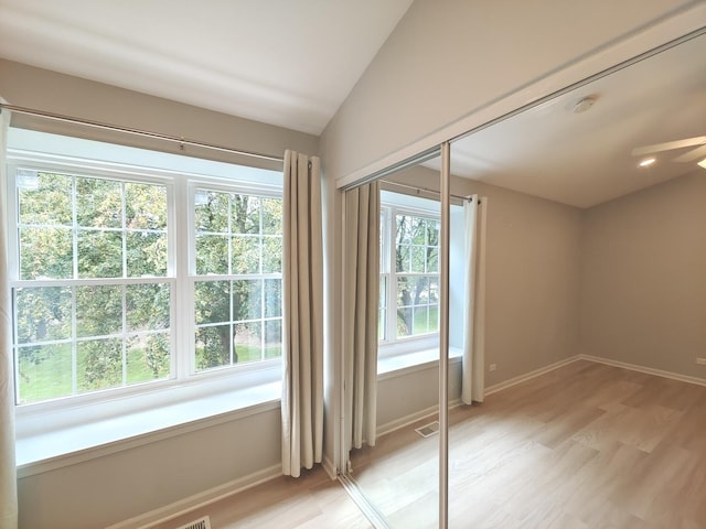 doorway featuring lofted ceiling, light wood-style floors, visible vents, and baseboards