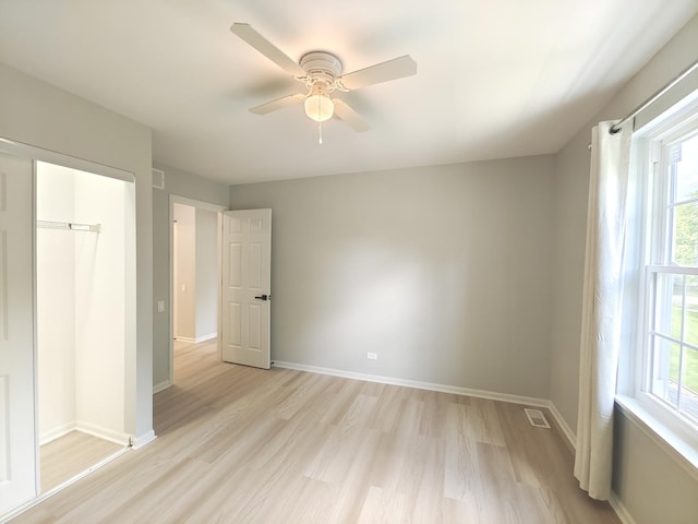 unfurnished bedroom featuring a ceiling fan, visible vents, light wood-style flooring, and baseboards