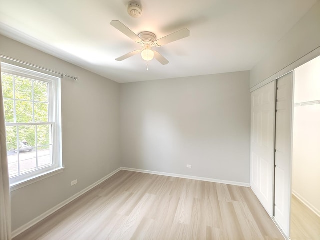 unfurnished bedroom with a ceiling fan, a closet, light wood-style flooring, and baseboards