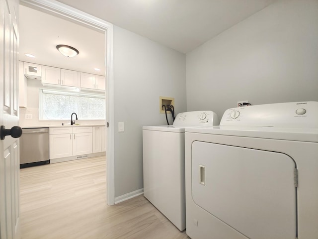 laundry area with light wood finished floors, a sink, laundry area, independent washer and dryer, and baseboards