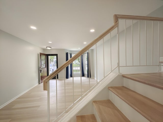 stairway featuring baseboards, wood finished floors, and recessed lighting