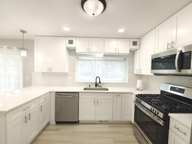kitchen featuring a peninsula, white cabinetry, stainless steel appliances, and a sink