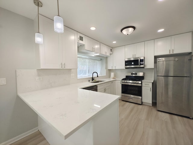 kitchen featuring a peninsula, white cabinetry, appliances with stainless steel finishes, and a sink