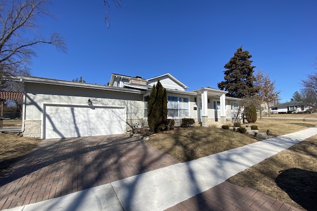 view of front of house featuring a garage, stone siding, and decorative driveway