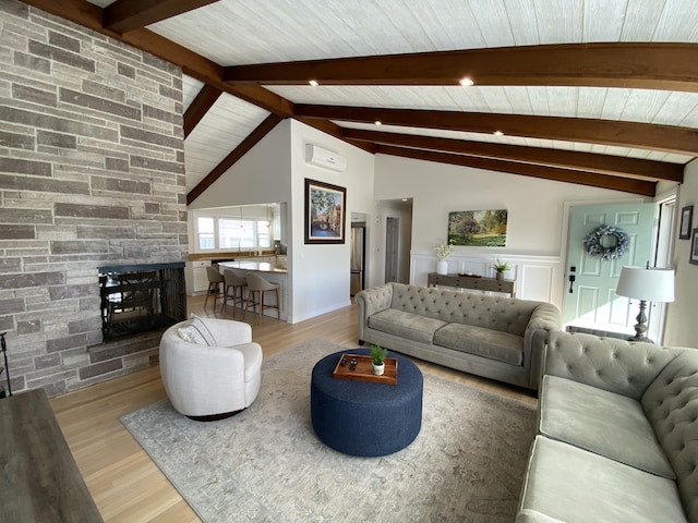 living room with vaulted ceiling with beams, a stone fireplace, and wood finished floors