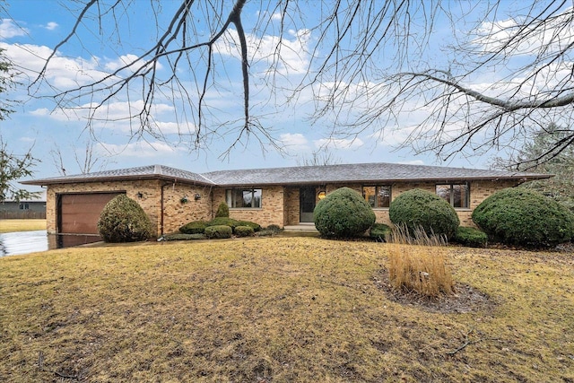 ranch-style home featuring driveway, brick siding, a front lawn, and an attached garage