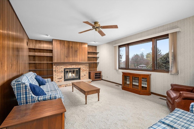 living area with baseboards, visible vents, a ceiling fan, light colored carpet, and a fireplace