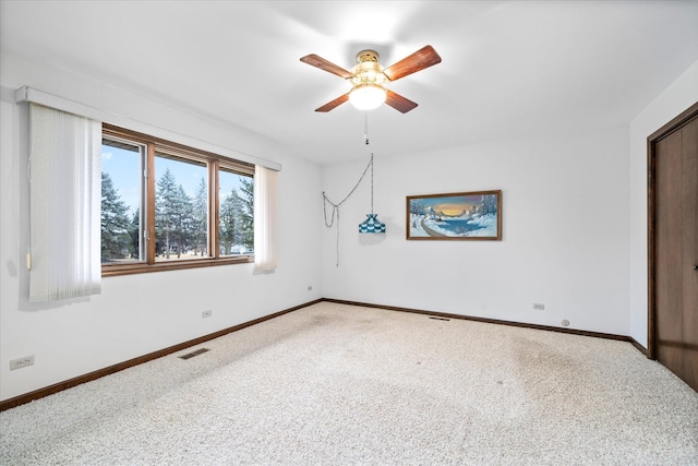 carpeted empty room featuring ceiling fan, visible vents, and baseboards