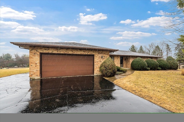 view of front facade featuring a front lawn, brick siding, driveway, and an attached garage