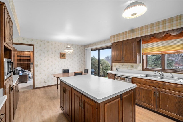 kitchen featuring a healthy amount of sunlight, stainless steel microwave, a sink, and wallpapered walls