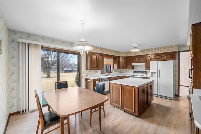 kitchen with white appliances, light countertops, under cabinet range hood, and wallpapered walls