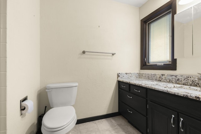 bathroom with toilet, vanity, and baseboards