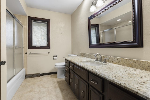 bathroom featuring baseboards, visible vents, toilet, shower / bath combination with glass door, and vanity