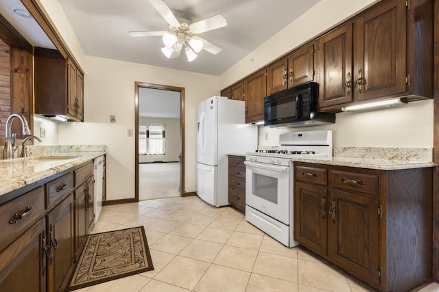 kitchen featuring dark brown cabinets, white appliances, light tile patterned flooring, and a sink