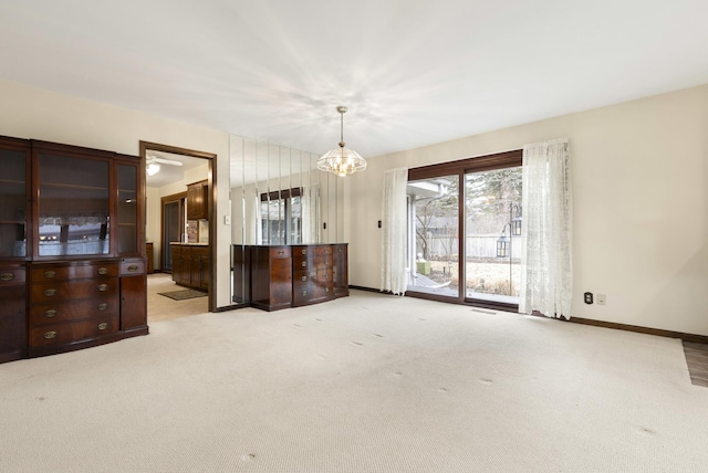 interior space with carpet, baseboards, and a notable chandelier